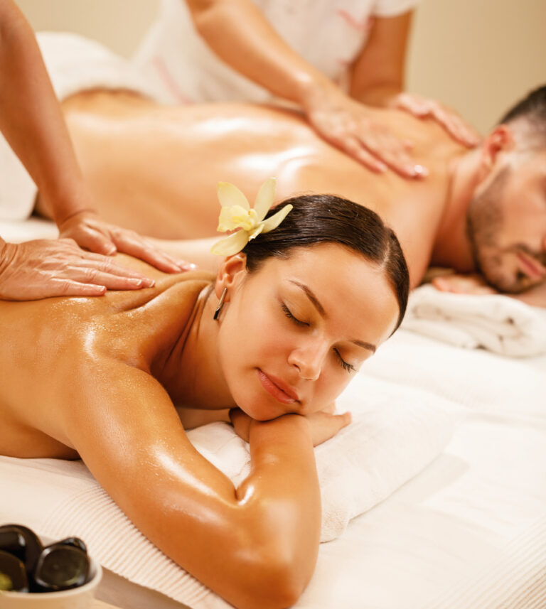 Young couple relaxing during back massage at health spa. Focus is on young woman.